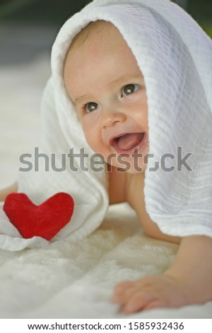 Baby boy under white towel, smiling