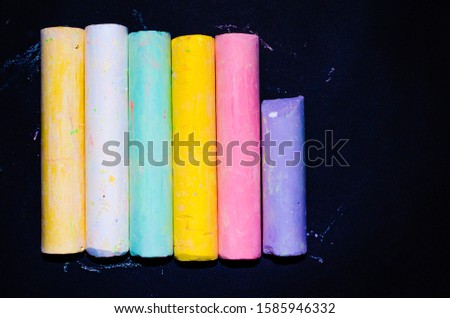 Children`s multicolored crayons on a black background. Chalk for drawing in different angles and different sides. Children's chalk for drawing in macro