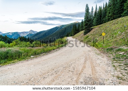 Wide angle view of green alpine mountains with dirt road leading to Ophir pass near Columbine lake trail in Silverton, Colorado in 2019 summer morning