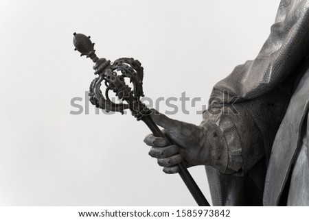 closeup of a black classical statue with hand holding an ornated large scepter Royalty-Free Stock Photo #1585973842