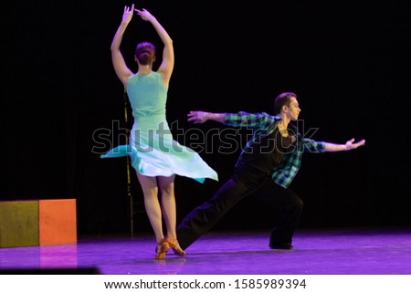 A pair of dancers a man and a woman perform in a theater on stage in a dance musical show.