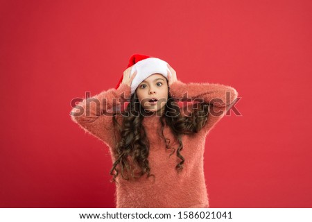 oh my god. little santa. happy new year. time for christmas holiday. small girl in santa hat. surprised child red background. winter kid fashion. favorite winter holiday. having fun.