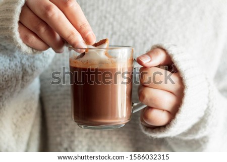Woman hands dipping cookie in hot chocolate