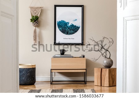Modern scandinavian living room interior with black mock up poster frame, design commode, flowers in vase, black rattan basket, macrame, books and elegant accessories. Template. Stylish home staging. 
