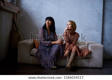 two women are sitting on the couch in the twilight