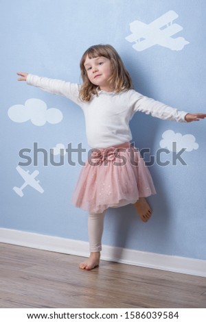 Happy little girl having fun on blue background with simple graphics. The imaginative concept for freedom, growth, future.