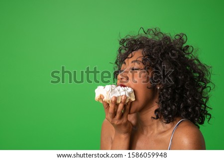 Close up of happy African American woman eating cake with whipped cream. Young attractive woman enjoying dessert on green screen
