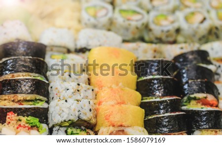 Fresh sushi rolls with salmon, avocado, tuna and cucumber. Maki plate with rice and nori. Delicious Japanese food with sushi roll in close up picture. Healthy kale and sushis. Holiday food dish.