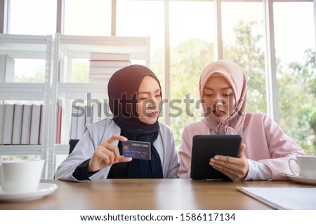 Muslim business woman in traditional clothing shopping online and paying with credit card