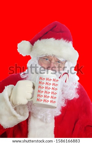 Santa Claus on red background. Santa Claus enjoys a mug of Hot Coco with whip cream and a Candy Cane with a Christmas Red background. Merry Christmas to all. 