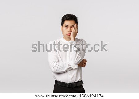 Oh god please make it stop. Annoyed, bothered and distressed young asian man waiting for something over, roll eyes and facepalm irritated, standing displeased, dont like party, think its boring Royalty-Free Stock Photo #1586194174