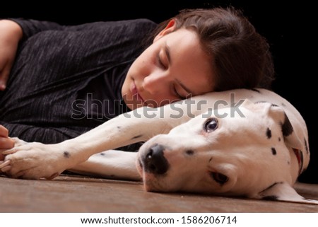 Stock photo of a teenage girl lying with her head on the body of a Dalmatian dog