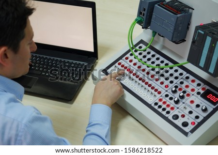 An operator is taking PLC course for Industry 4.0 preparation in a automation education center. Engineer is learning how to program a PLC. Selective focus. Royalty-Free Stock Photo #1586218522