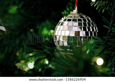 Closeup image of silver mirrored mosaic Christmas ornament hanging on Christmas tree.