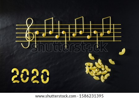 Musical Italian pasta 2020 in the form of notes, isolated on a black textural background. The concept of cooking as art.