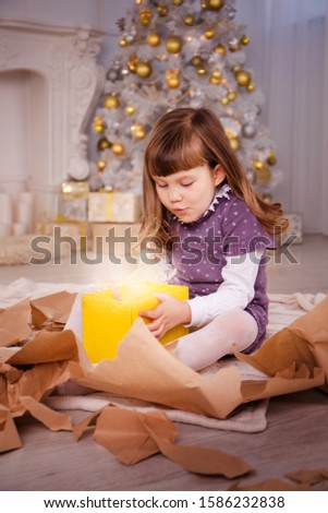 girl opens gifts near the Christmas tree