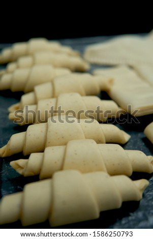 Pre-baked and raw croissant dough on metal baking tray                           