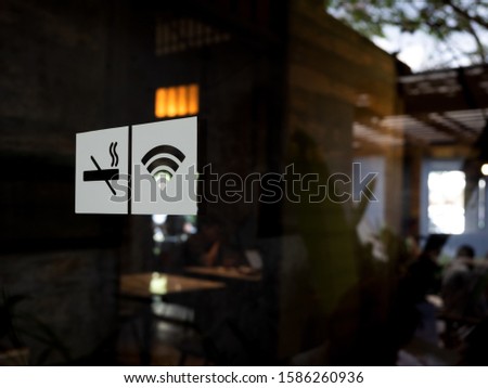 Signs on glass door. No smoking sign, wireless signal icon sign for free wifi on cafe background with copy space. Decal sticker signs pasted on front door outside the coffee shop.