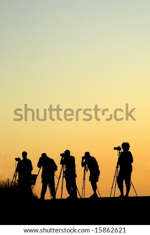 Silhouette of five photographers lined up shooting photos