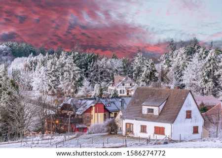 Landscape - picture in the spirit of winter Christmas , with snow-trimmed fir trees and traditional houses-with a sunset in flames