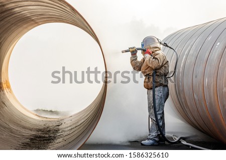 View of the manual sandblasting or abrasive blasting in the construction site. The difference between sandblasting and grit blasting, as shot blasting is often called, is straightforward. Royalty-Free Stock Photo #1586325610