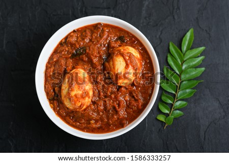 Egg roast curry or Mutta roast gravy dish popular spicy Kerala food on dark black background Tamil Nadu South India. Top view of Indian non veg side dish for rice, Appam, Chapati, Porotta, Parantha . Royalty-Free Stock Photo #1586333257