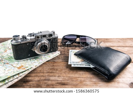Wallet, vintage camera, map and money on wooden background isolated on white. Travel concept