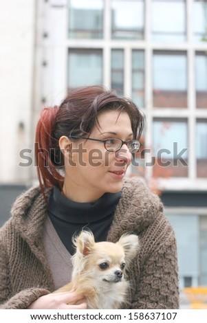A woman with chihuahua in her lap on an autumn day