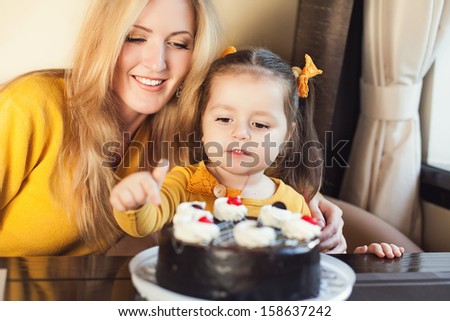 Mom and young daughter celebrating a birthday with cake