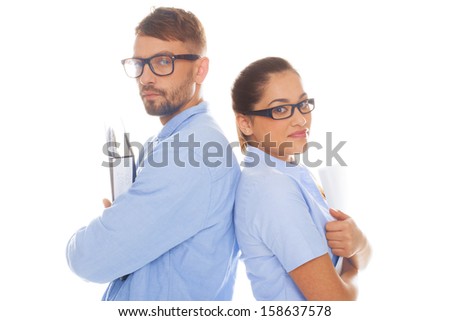 Professional and nerdy looking couple leaning back to back holding documents and wearing formal blue shirts in a white background
