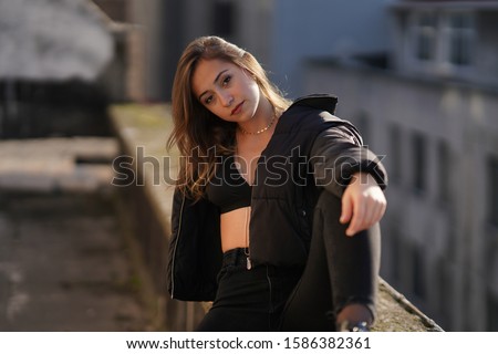 dancer girl in black pants, jacket, high heels and bra on the roof