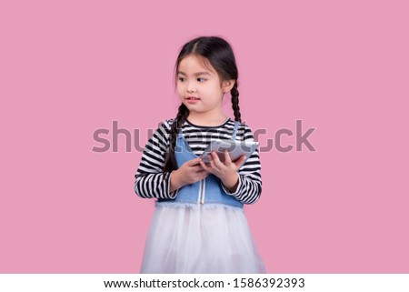 Children girl ,are learning technology Laptop or mobile phone with . isolated on pink background