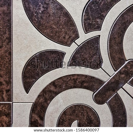 White and brown ceramic tiles with floral pattern for wall and floor decor. Concrete stone surface background. Texture with frame for interior design project.