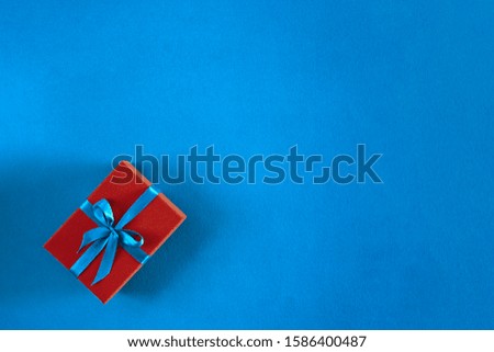 Christmas red gift box on blue background with copy space. Flat lay. Top view.