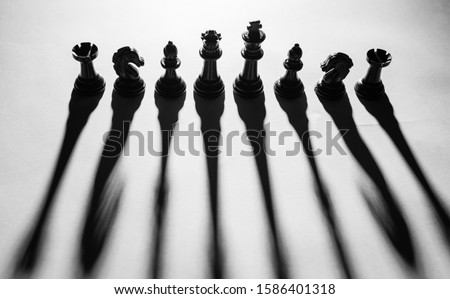 Top angle silhouette of chess pieces with long and extended shadows. Black chess pieces. Game of chess