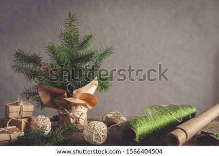 Christmas and zero waste, eco friendly packaging. Woman is wrapping gifts in craft paper on a wooden table, ecological Christmas holiday concept, eco decor