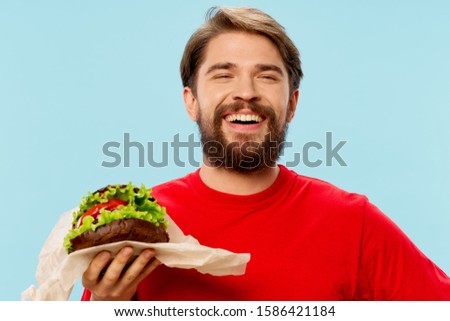 A man in a red T-shirt with a hamburger in his hand Emotions beard mustache fast food