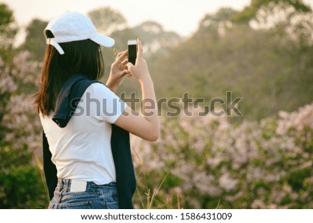 A woman standing to take pictures of the scenery with the phone