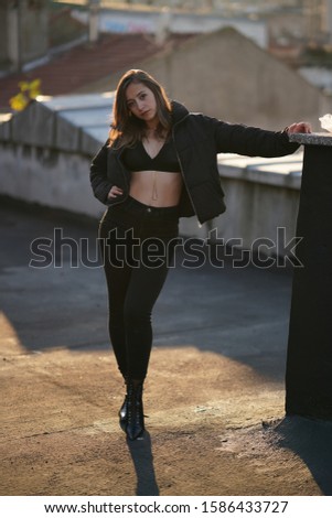 dancer girl in black pants, jacket, high heels and bra on the roof