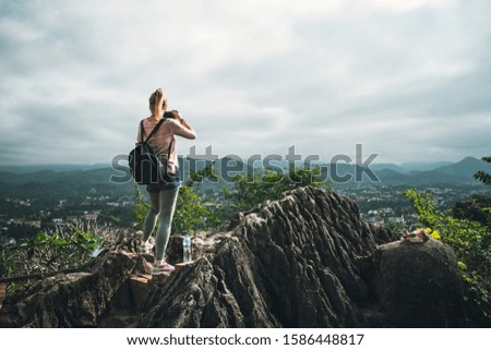 female tourist takes picture of on top of Phousi mountain in Luang Prabang, Laos