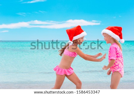 Adorable kids in Santa hats celebrating Christmas on the beach