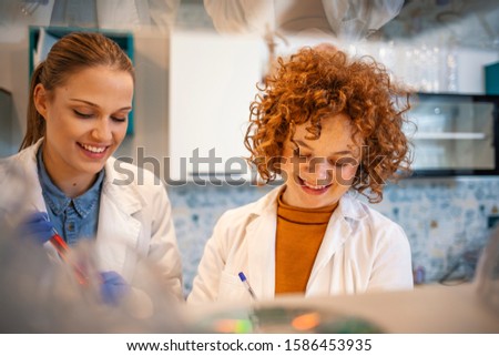 Two scientists are working in laboratory. Young female researcher and her supervisor are doing investigations on laboratory equipment. Busy scientists working in chemistry lab