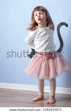 Little girl playing an imaginative game on blue background. Simple graphic of a cat hidden behind the child.