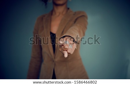 Selective focus on the hand (with rings) of a black woman pointing at you
