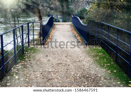 a wooden bridge with metal railing over the river