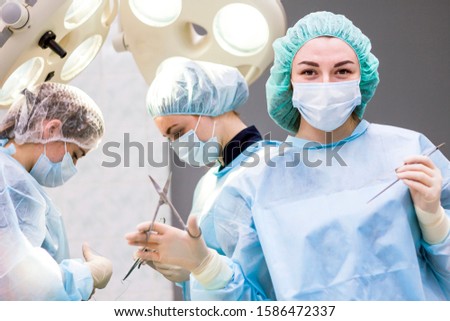Female surgeon during surgery with medical instruments in her hands. The woman in the operating room is looking directly at the camera. Woman Resuscitator in intensive care