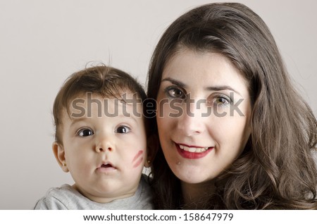 Portrait of mother and baby. Kiss mark on baby face.