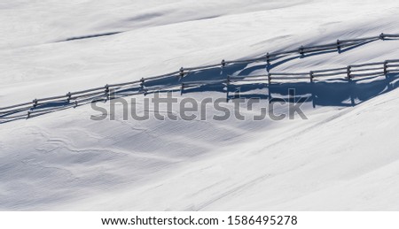 A fence in a winter landscape with fresh snow.
