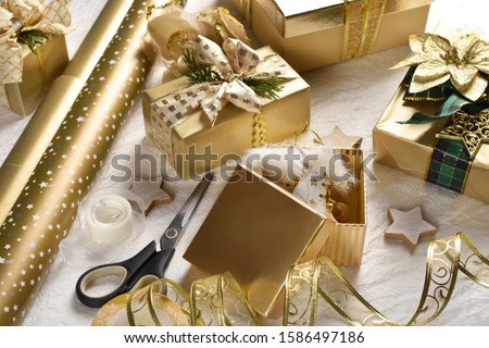packing Christmas presents in glamour style with golden color paper and ribbon