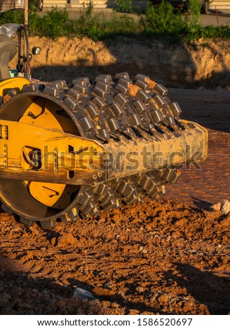Soil compactor with vibratory padfoot drum. Heavy duty machinery working on highway construction site. Vehicle for soil compaction. Road construction equipment. Paving. Compaction of the road.